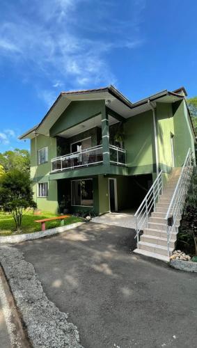 una casa verde con una escalera delante de ella en Casa das Bromélias- Com Quiosque em meio à natureza! en Piratuba