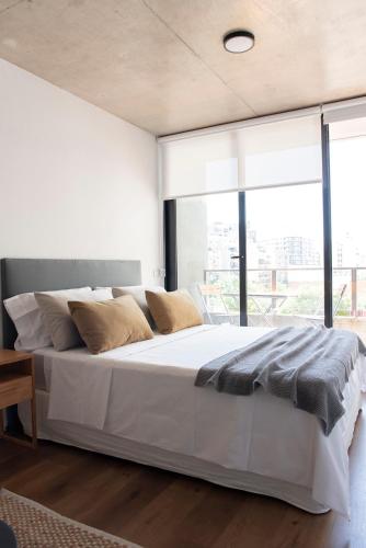 1 dormitorio con 1 cama blanca grande y ventana grande en Palermo area, modern studio, digital nomads heaven en Buenos Aires