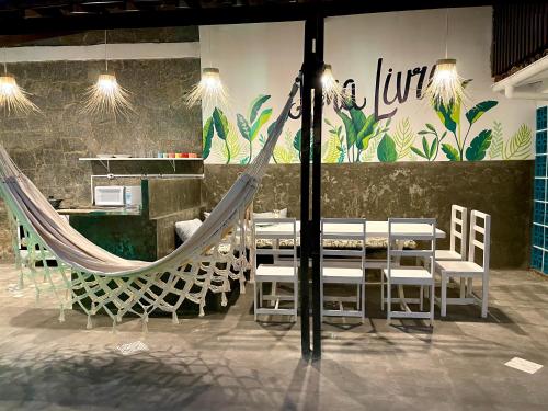 a restaurant with chairs and a hammock in a room at Alma Livre Pipa Casa de Praia in Pipa