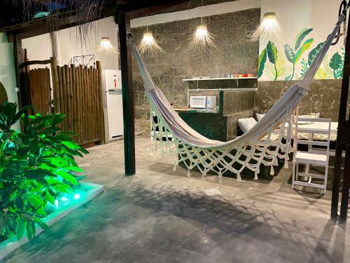 a hammock in a room with tables and chairs at Alma Livre Pipa Casa de Praia in Pipa