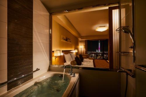 a bathroom with a tub and a large mirror at Asakusa View Hotel in Tokyo