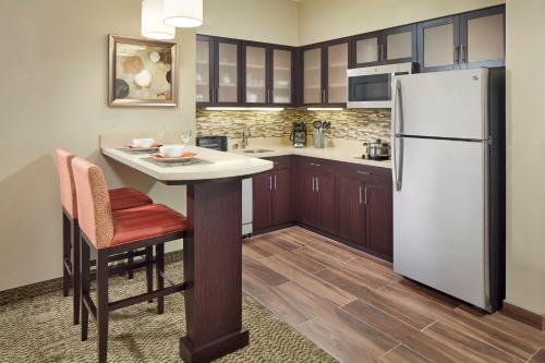 a kitchen with a white refrigerator and a table at Staybridge Suites Anaheim At The Park by IHG in Anaheim
