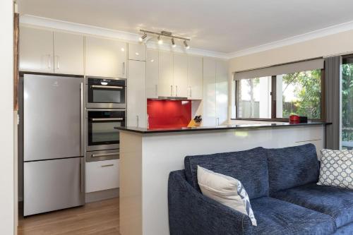 a living room with a blue couch and a kitchen at Wallis Gardens 11 in Forster