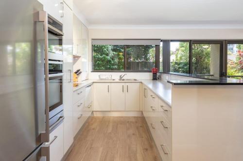 a kitchen with white cabinets and a large window at Wallis Gardens 11 in Forster