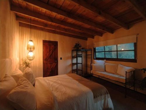 ein Schlafzimmer mit einem Bett, einem Sofa und einem Fenster in der Unterkunft Cálido Bungalow 3 - La Locanda casitas vivas - in Balneario Buenos Aires