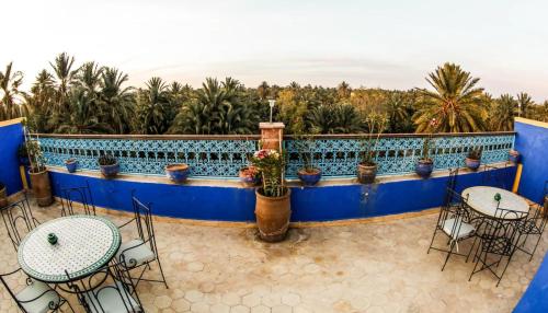 a patio with tables and chairs and palm trees at Dar marco polo in Erfoud