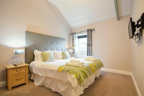 een slaapkamer met een groot bed en 2 handdoeken bij Dunlin Cottage - Lucker Steadings in Lucker