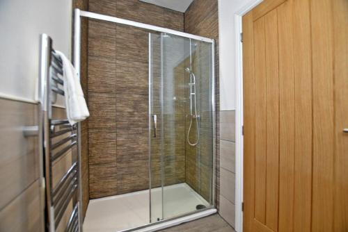 een douche met een glazen deur in de badkamer bij Dunlin Cottage - Lucker Steadings in Lucker