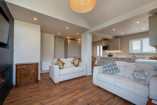 a living room with two white couches and a kitchen at Castle View Bamburgh in Bamburgh