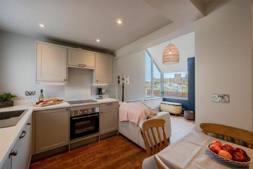a kitchen with white cabinets and a table with a bowl of fruit at Castle View Bamburgh in Bamburgh