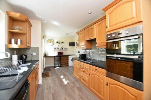 a large kitchen with wooden cabinets and black counter tops at Armstrong Cottages No22 in Bamburgh