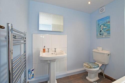a white bathroom with a sink and a toilet at Beach Retreat in Seahouses