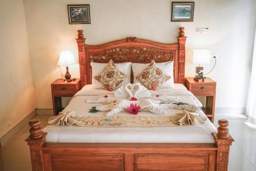 a bed with a wooden frame with flowers on it at Amed Cafe & Hotel Kebun Wayan in Amed