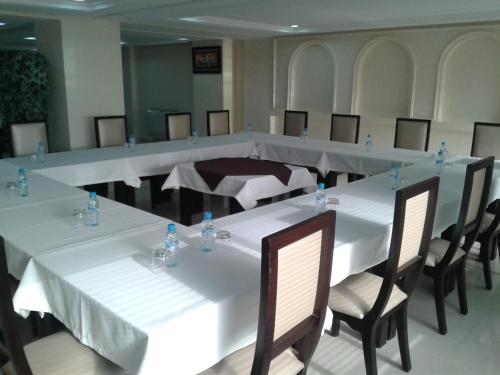 a long table in a room with white tables and chairs at Al Akhawayn in Oujda