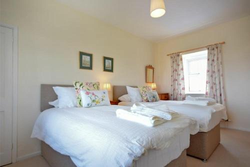 a bedroom with two beds with white sheets and a window at Dunrovin in Beadnell