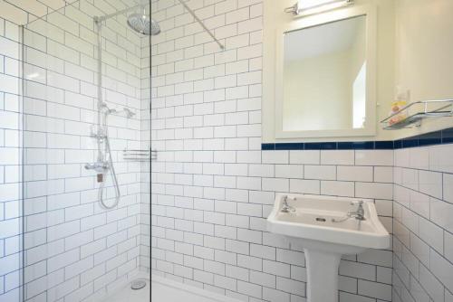 uma casa de banho em azulejos brancos com um lavatório e um chuveiro em Dunrovin em Beadnell