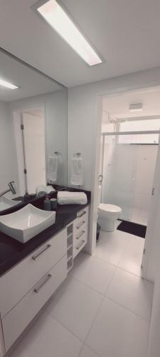 a white bathroom with a sink and a toilet at Fantástica casa 4 quartos próxima a praia em condomínio fechado ! in Aracaju