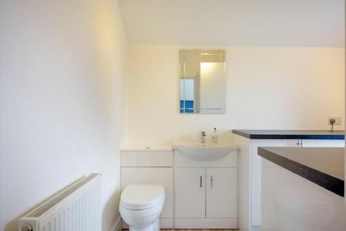 a white bathroom with a toilet and a sink at Viewpoint in Alnmouth