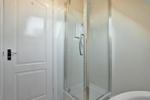 a shower with a glass door in a bathroom at Annstead House in Seahouses
