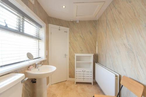 a bathroom with a sink and a bath tub and a sink at Dairyman's Cottage in Amble