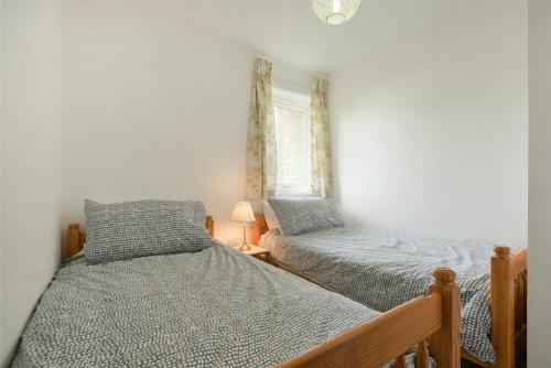 a bedroom with two twin beds and a window at Coastal Plaice in Beadnell