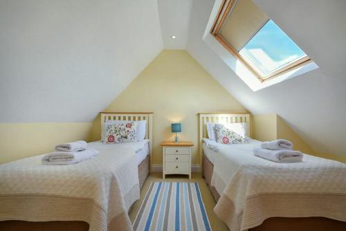 a attic room with two beds and a window at Grange Cottage in Alnmouth