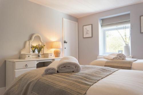 a bedroom with two beds and a desk and a window at Creel Cottage, Craster in Craster