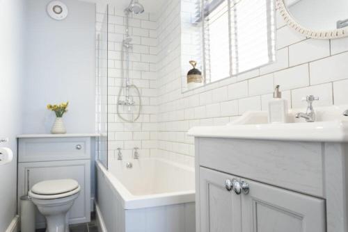 a bathroom with a white tub and a sink and a toilet at Creel Cottage, Craster in Craster