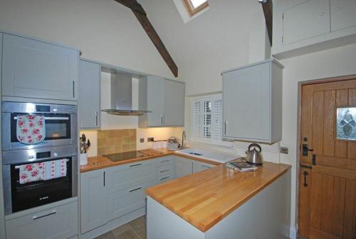 a kitchen with white cabinets and a wooden counter top at Martins Cottage in Alnmouth