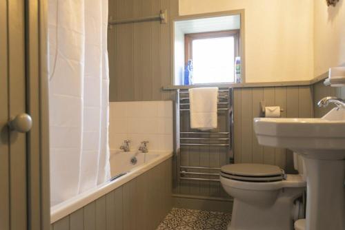 a bathroom with a toilet and a sink and a tub at Kittiwake Cottage, Seahouses in Seahouses