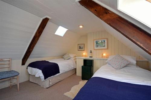 a attic room with two beds and a table at Pebble Cottage in Long Houghton