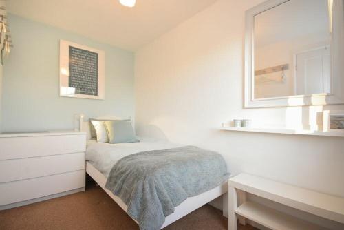 a white bedroom with a bed and a mirror at Barmoor in Embleton