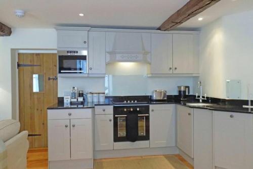 a kitchen with white cabinets and a stove top oven at Dorothy Forster Court in Alnwick