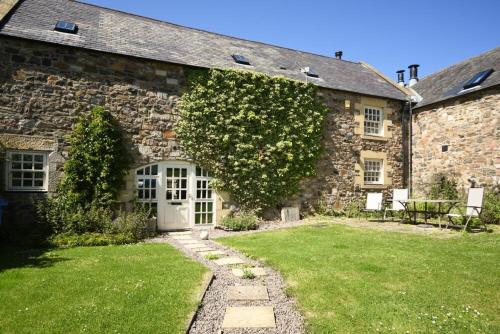 an old stone house with a green yard at Budle Granary in Bamburgh