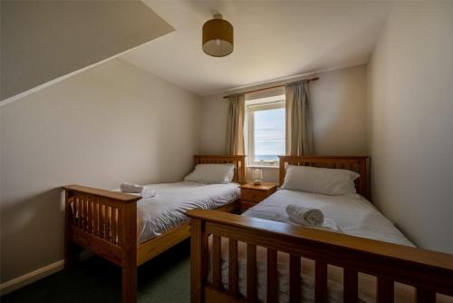 1 dormitorio con 2 camas y ventana en Fidra, en Embleton