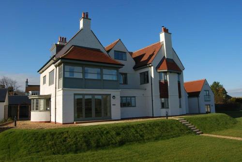 a large white house with a red roof at Sandpiper Bamburgh in Bamburgh