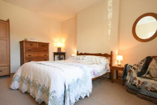 a bedroom with a bed and a dresser and a mirror at Kittiwake Cottage, Budle Bay in Bamburgh