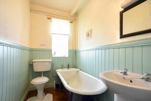 uma casa de banho com um WC, um lavatório e uma banheira em Kittiwake Cottage, Budle Bay em Bamburgh