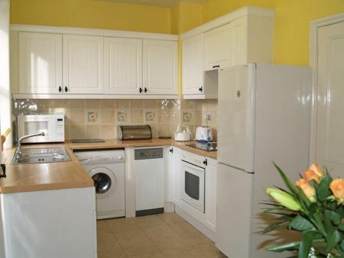 a kitchen with white cabinets and a white refrigerator at Briar Cottage in Wark