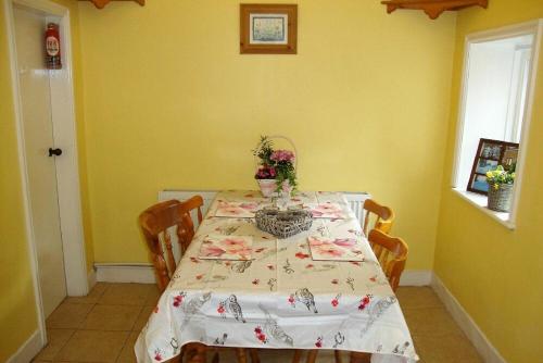 a dining room table with a white table cloth and flowers on it at Briar Cottage in Wark