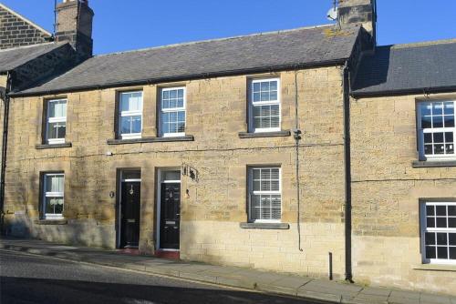 an old brick building on the side of a street at Crier Cottage in Alnwick