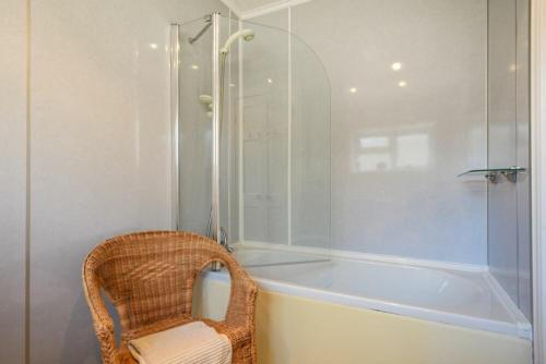 uma casa de banho com uma cadeira de vime ao lado de uma banheira em Crier Cottage em Alnwick