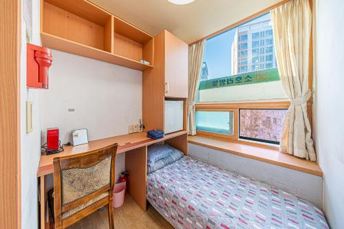 ソウルにあるDream Single Houseのデスク、ベッド、窓が備わる小さな客室です。