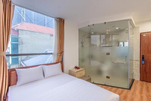 1 dormitorio con 1 cama y ducha acristalada en Coco Hotel Cau Giay en Hanói