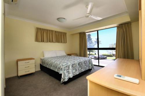 Schlafzimmer mit einem Bett, einem Schreibtisch und einem Fenster in der Unterkunft Coral Sands Apartment 201 in Bargara
