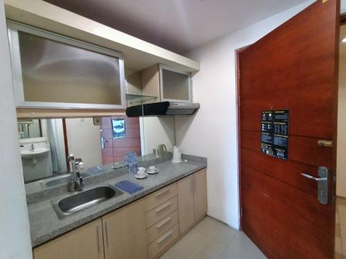 cocina con fregadero y puerta de madera en High Point Serviced Apartment en Surabaya