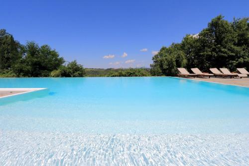 a large swimming pool with chairs and blue water at Castello di Bibbione in San Casciano in Val di Pesa