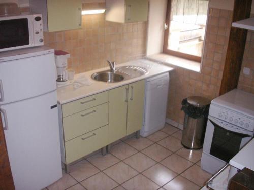 une cuisine avec un évier et un réfrigérateur blanc dans l'établissement Gîte Climatise Près de la Sioule avec Jardin Privatif, Terrasse et Tout Confort - FR-1-489-96, à Saint-Germain-de-Salles