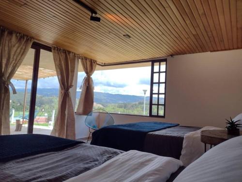 1 dormitorio con 2 camas y ventana grande en Fogata Naturaleza y Descanso, Casa de Campo Eucaliptos, en Iza