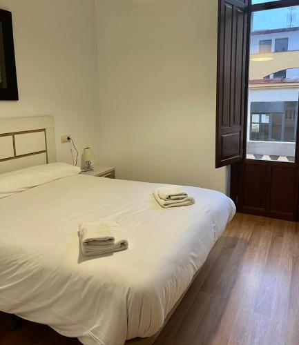 a bedroom with a white bed with towels on it at María Cristina 2 in Córdoba